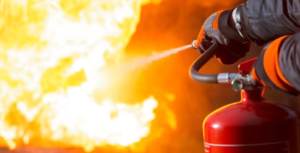 A person using a fire extinguisher to put out intense flames.